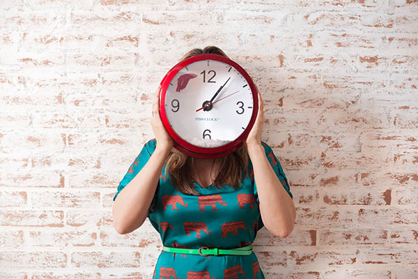 Woman Holding Clock Over Face